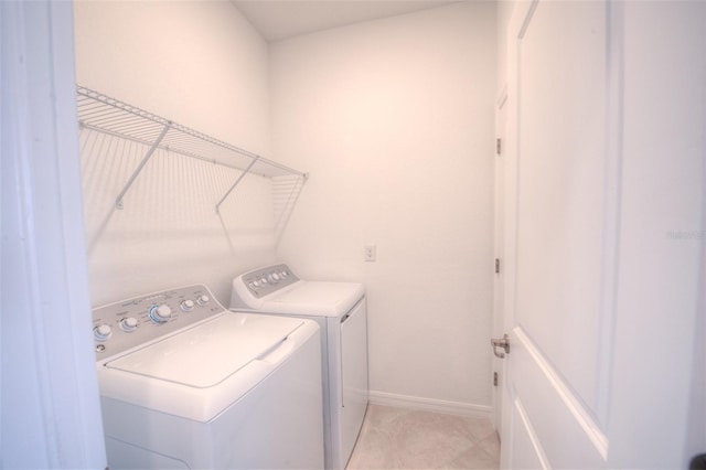 clothes washing area with separate washer and dryer, baseboards, and light tile patterned flooring