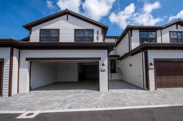 view of front of house featuring decorative driveway, an attached garage, and stucco siding