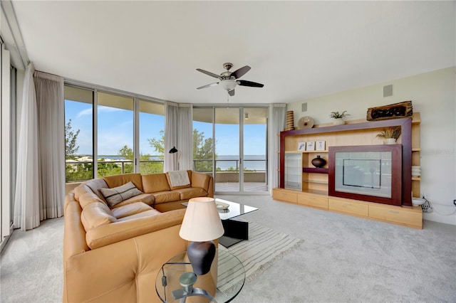 living room with a wall of windows, a water view, light colored carpet, and ceiling fan