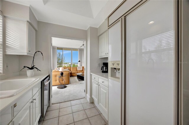 kitchen featuring white cabinetry, white fridge with ice dispenser, light tile patterned flooring, and stainless steel dishwasher