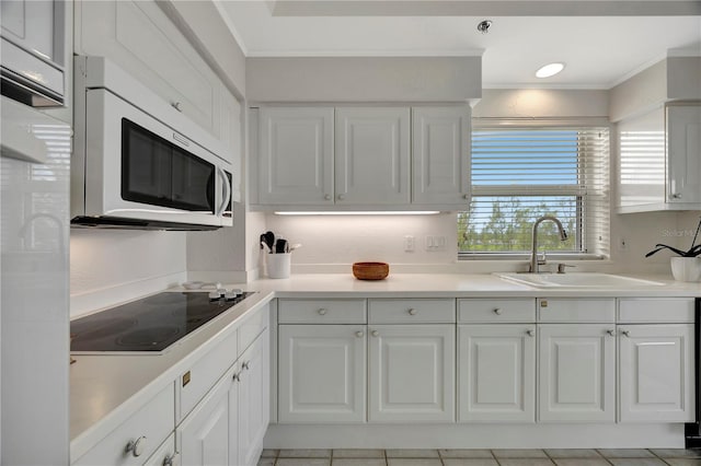 kitchen featuring light tile patterned floors, white cabinetry, black electric cooktop, ornamental molding, and sink