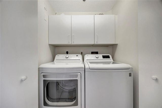 washroom with independent washer and dryer, a textured ceiling, and cabinets