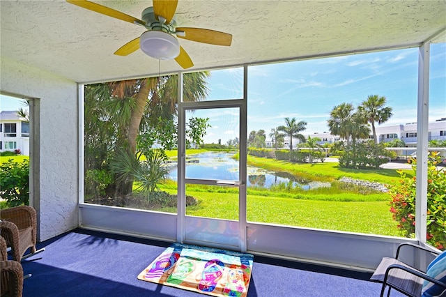 sunroom with plenty of natural light, ceiling fan, and a water view