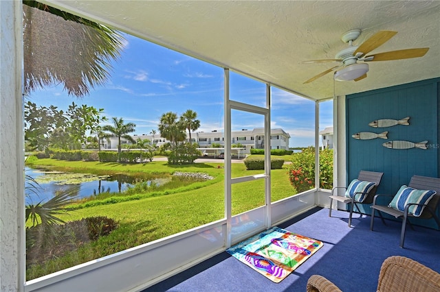 sunroom featuring a water view and ceiling fan