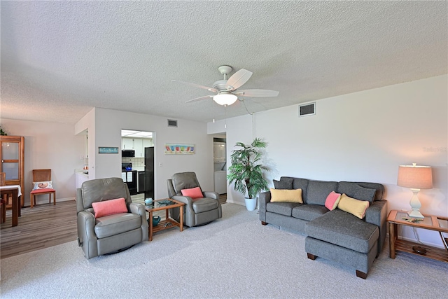 carpeted living room with ceiling fan and a textured ceiling