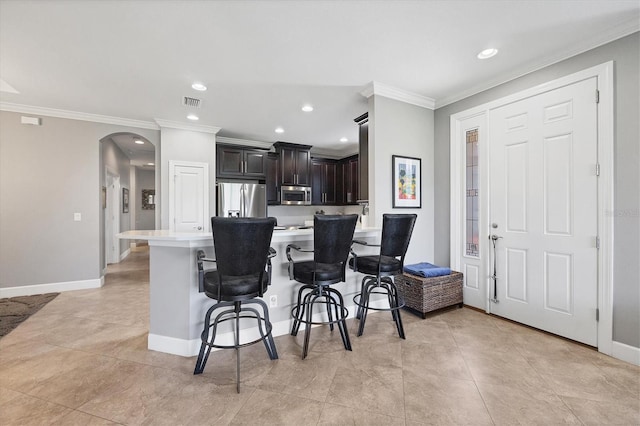 kitchen with light tile patterned floors, a breakfast bar, stainless steel appliances, and dark brown cabinets