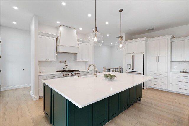 kitchen featuring white cabinets, custom exhaust hood, pendant lighting, and light wood-type flooring