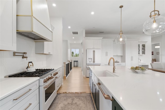 kitchen featuring white cabinetry, high end white range oven, and decorative light fixtures