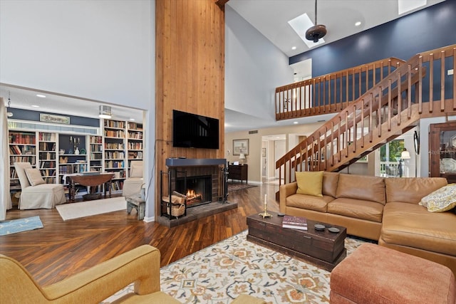 living room with a large fireplace, hardwood / wood-style flooring, and high vaulted ceiling