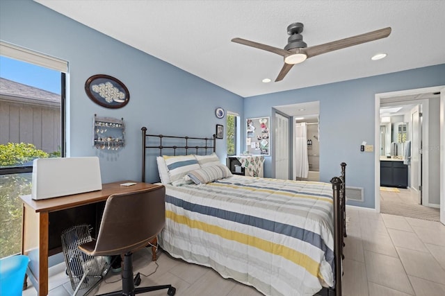 bedroom with a textured ceiling, ensuite bath, multiple windows, and ceiling fan