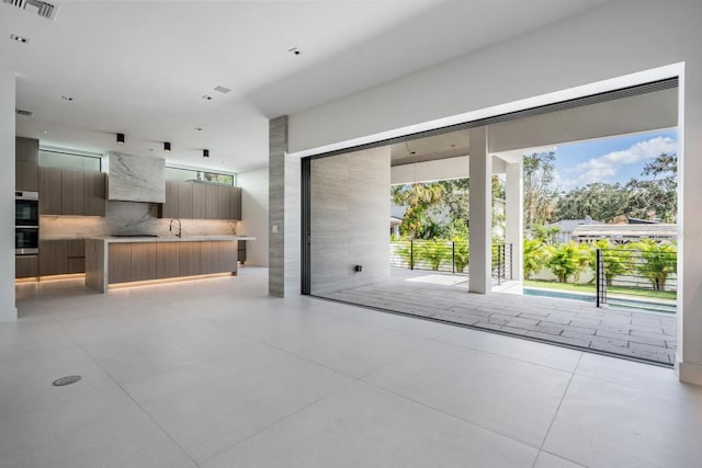 kitchen with stainless steel double oven, sink, a center island, light tile patterned floors, and tasteful backsplash