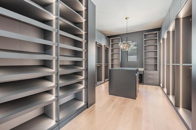 spacious closet with a chandelier and light hardwood / wood-style floors