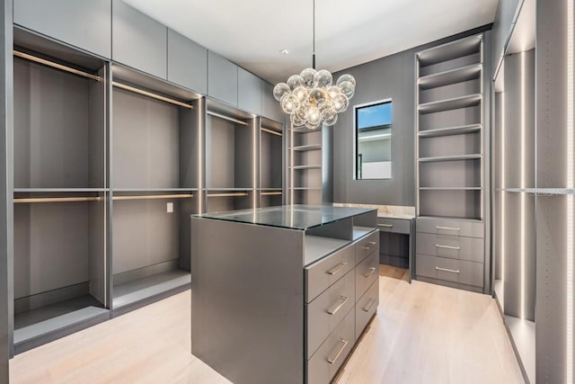 walk in closet featuring an inviting chandelier and light hardwood / wood-style floors