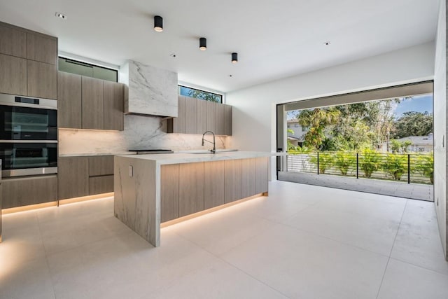 kitchen featuring stainless steel double oven, sink, a center island, light tile patterned floors, and tasteful backsplash