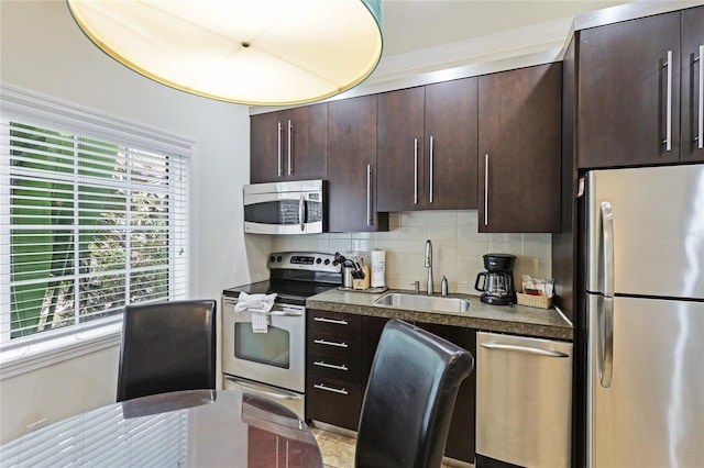 kitchen with appliances with stainless steel finishes, dark brown cabinets, tasteful backsplash, and sink