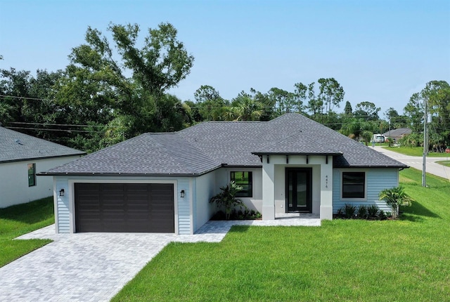 view of front of house with a front lawn, decorative driveway, an attached garage, and a shingled roof