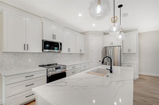 kitchen featuring a center island with sink, appliances with stainless steel finishes, white cabinetry, and decorative backsplash