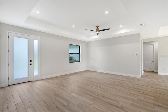 empty room featuring a tray ceiling, recessed lighting, visible vents, light wood-style floors, and baseboards