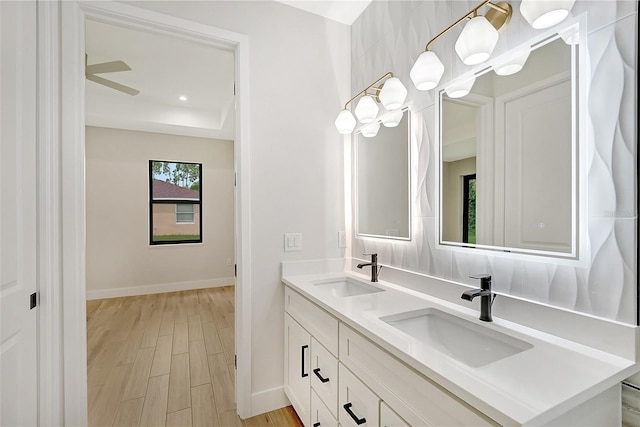 full bath with double vanity, baseboards, a sink, and wood finished floors