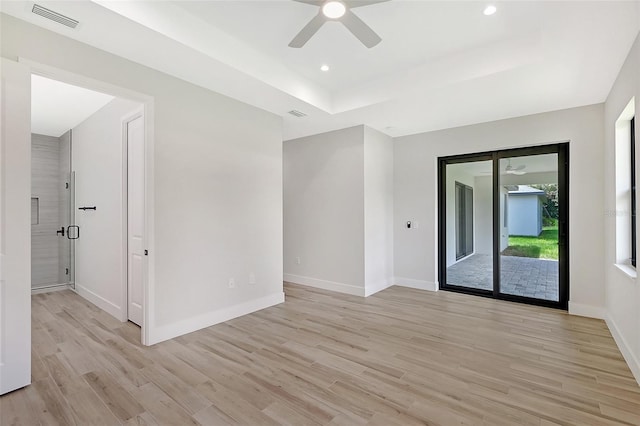 spare room with recessed lighting, visible vents, baseboards, light wood finished floors, and a tray ceiling