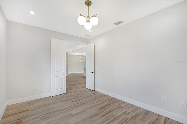 spare room featuring recessed lighting, visible vents, baseboards, light wood-type flooring, and an inviting chandelier