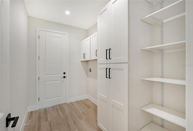 laundry room featuring light wood-style floors, baseboards, washer hookup, and cabinet space