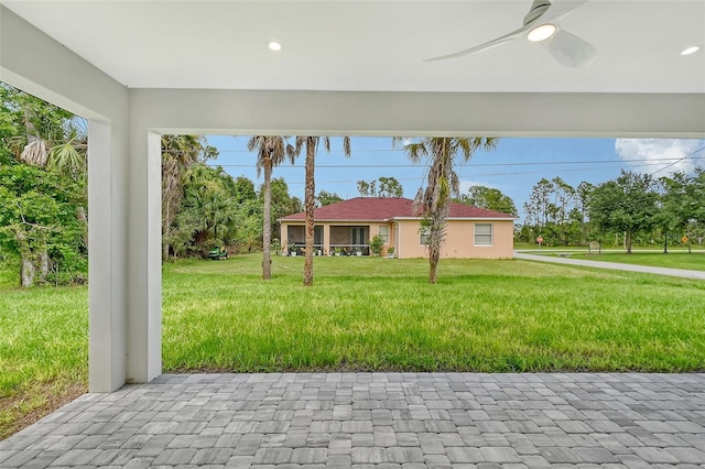 view of front of property featuring a front lawn, a ceiling fan, and stucco siding