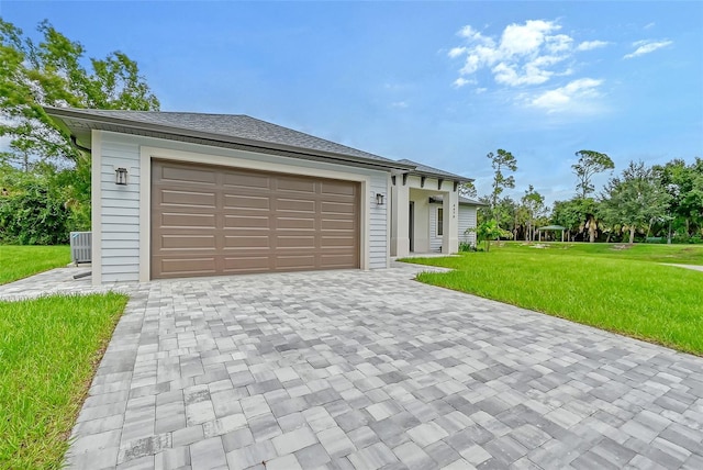 exterior space featuring a front yard, decorative driveway, roof with shingles, and an attached garage