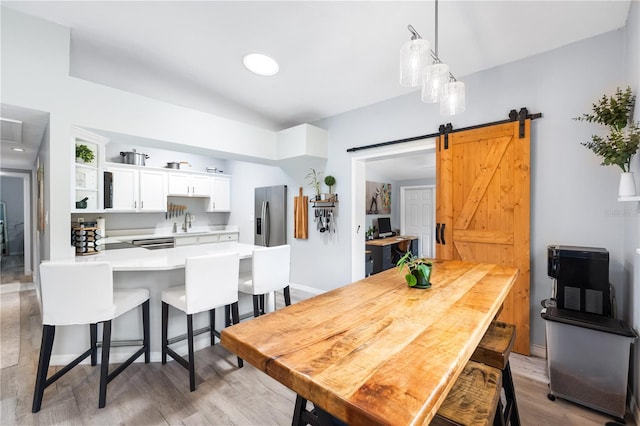 dining area featuring a barn door, sink, and light hardwood / wood-style flooring