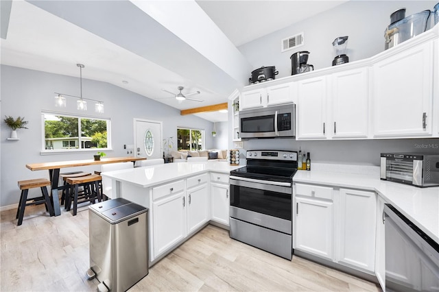 kitchen with vaulted ceiling, appliances with stainless steel finishes, kitchen peninsula, white cabinetry, and ceiling fan