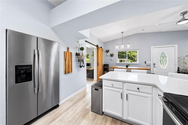 kitchen featuring white cabinets, a barn door, light wood-type flooring, lofted ceiling, and stainless steel fridge