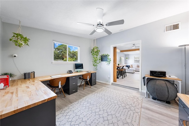 home office with light wood-type flooring and ceiling fan