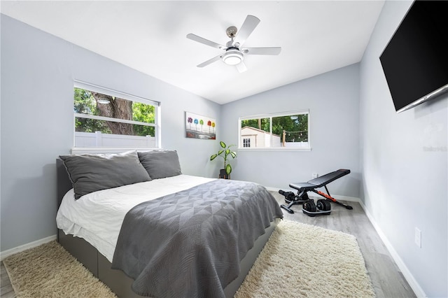 bedroom with ceiling fan, light hardwood / wood-style floors, and vaulted ceiling