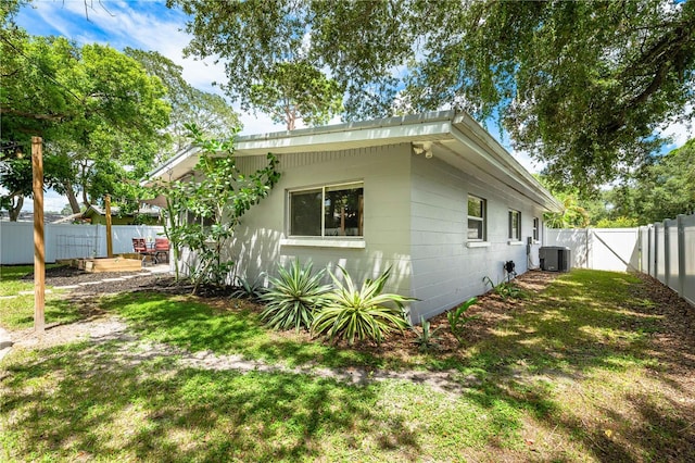 view of side of home featuring central AC unit and a lawn