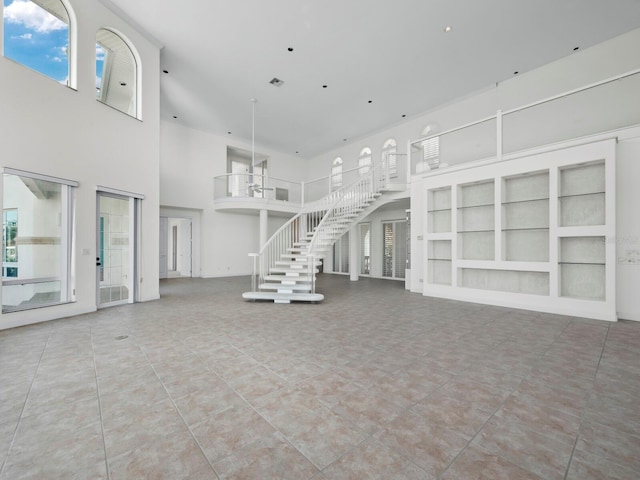 unfurnished living room with a high ceiling, tile patterned floors, and built in shelves