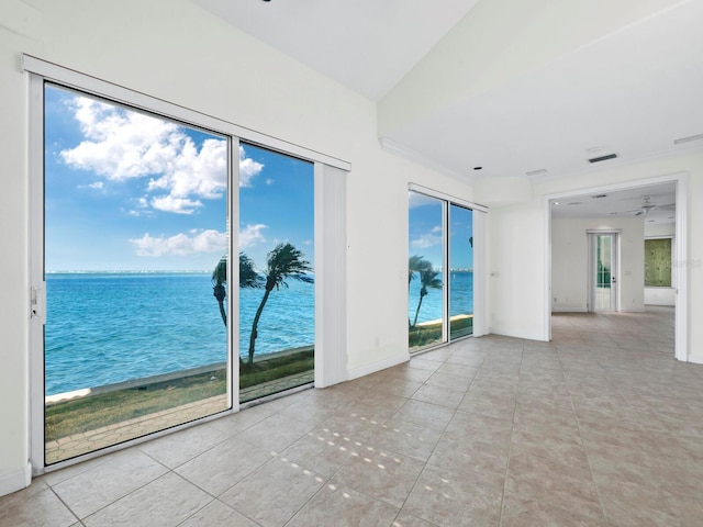 spare room with light tile patterned floors, a water view, plenty of natural light, and ceiling fan