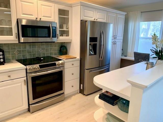 8630 Midnight Pass Rd Unit 103A, Sarasota, FL 34242 - kitchen with appliances with stainless steel finishes, light wood-type flooring, light countertops, decorative backsplash, and white cabinetry