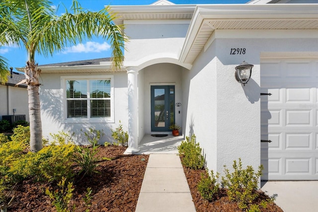 property entrance featuring a garage and stucco siding