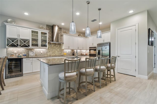 kitchen with a kitchen island with sink, wall chimney exhaust hood, white cabinetry, and wine cooler