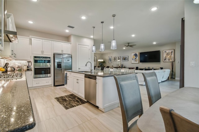 kitchen featuring a center island with sink, appliances with stainless steel finishes, sink, ceiling fan, and white cabinets