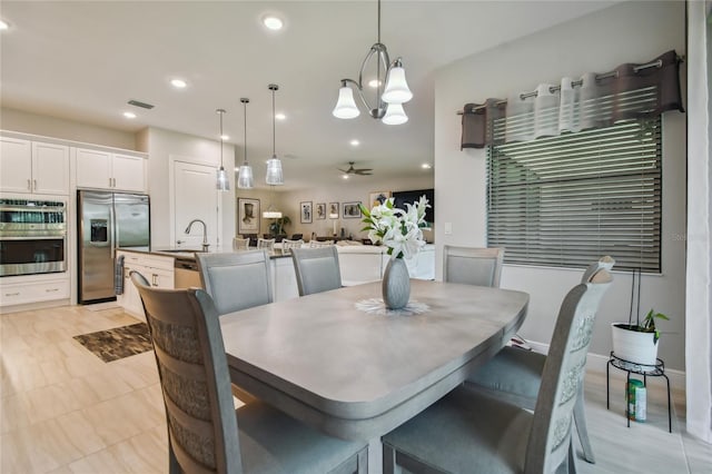 dining area featuring ceiling fan with notable chandelier and sink