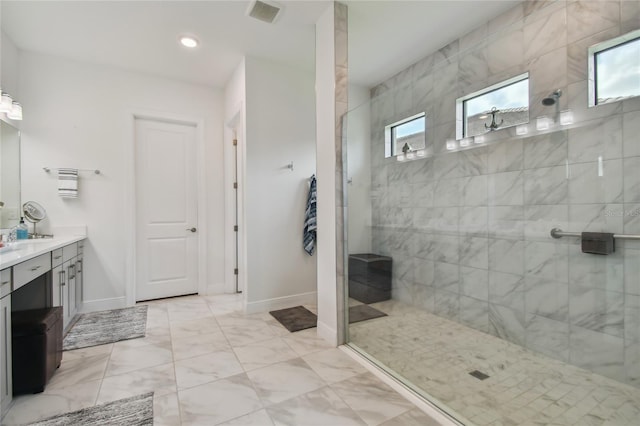 bathroom with a tile shower and vanity