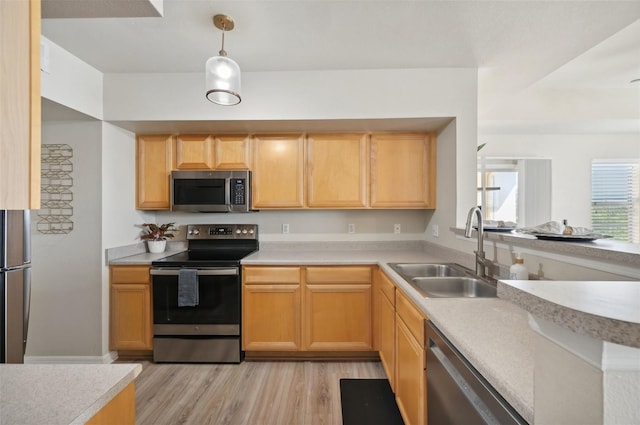 kitchen featuring sink, hanging light fixtures, light brown cabinets, light wood-type flooring, and appliances with stainless steel finishes