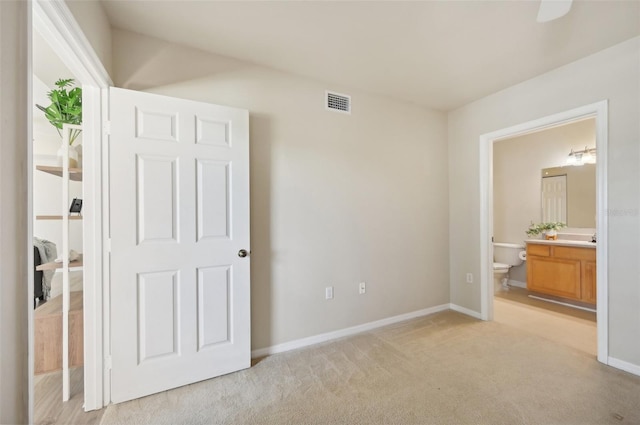 unfurnished bedroom featuring connected bathroom and light colored carpet