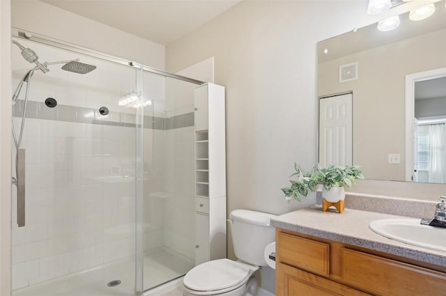 bathroom featuring a shower with door, vanity, and toilet