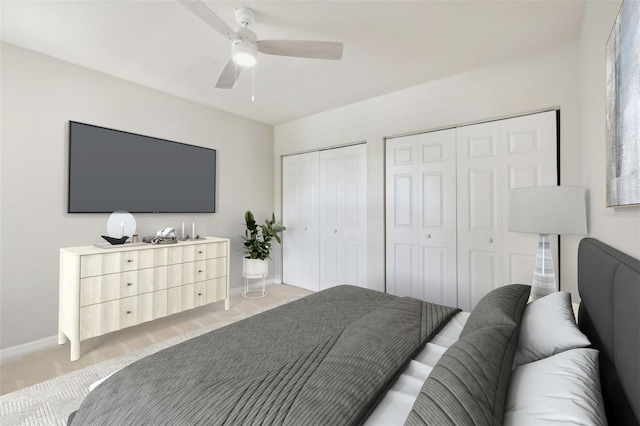 bedroom featuring two closets, light colored carpet, and ceiling fan