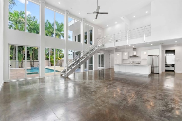 unfurnished living room featuring a towering ceiling and ceiling fan