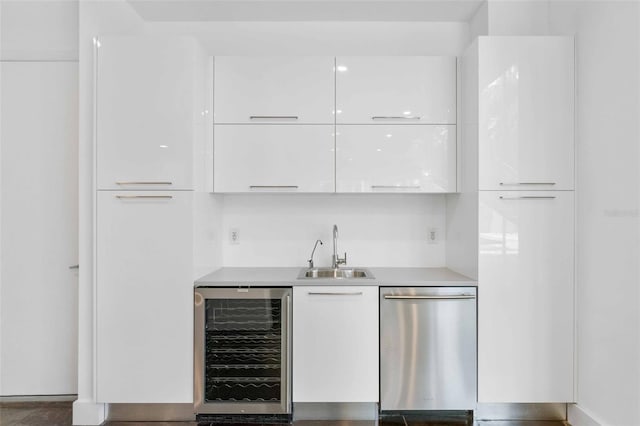 bar with beverage cooler, white cabinets, sink, and stainless steel dishwasher