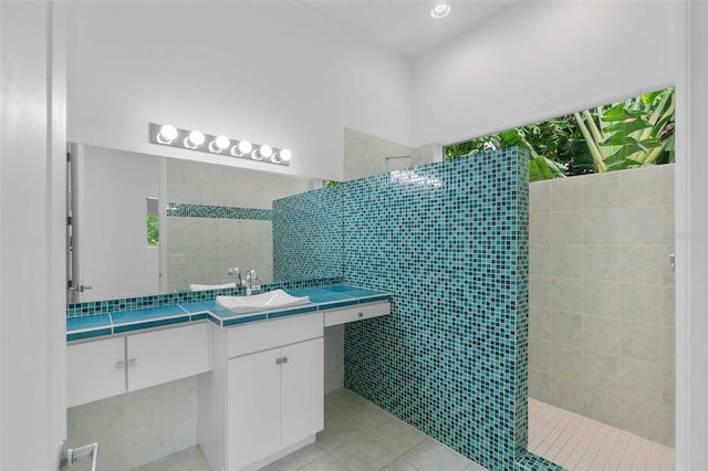 bathroom with walk in shower, vanity, tile walls, and tile patterned flooring