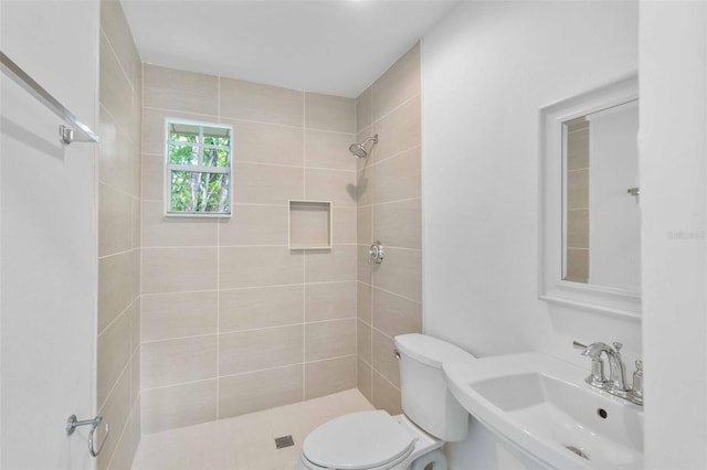 bathroom with sink, toilet, and tiled shower